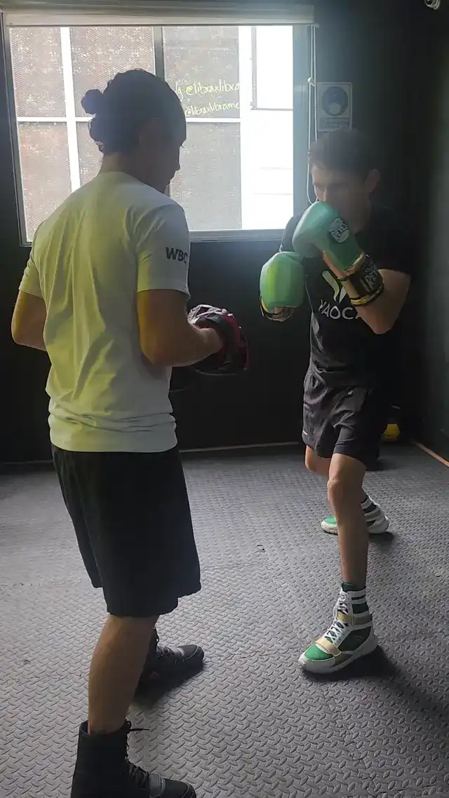 Entrenador guiando la técnica de boxeo de una alumna en Libra x Libra